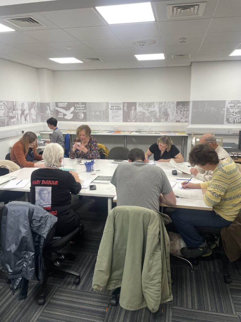 seven people sitting around a large white table in a white room.